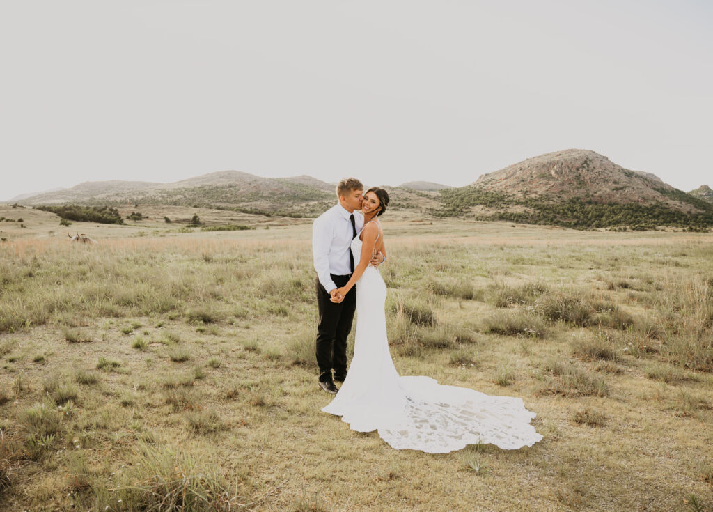 A couple stands kissing in the Wichita mountain wildlife refuge on their elopement day. One of the best places to elope in oklahoma.