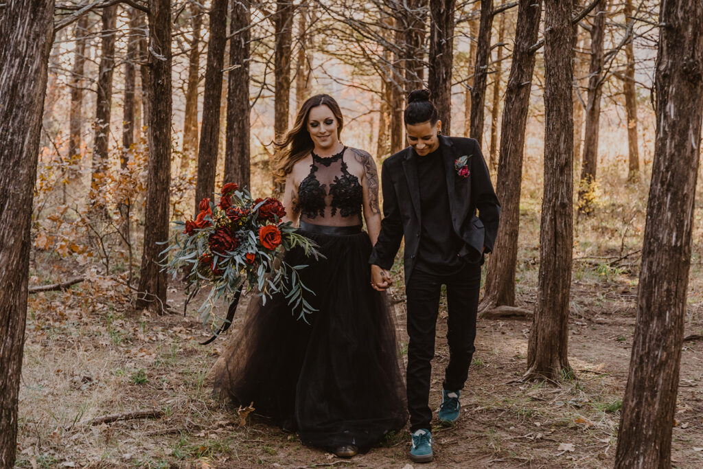 A LGBTQ couple walks while holding hands. They are dressed in all black on their elopement day in the Wichita mountains of Oklahoma. 