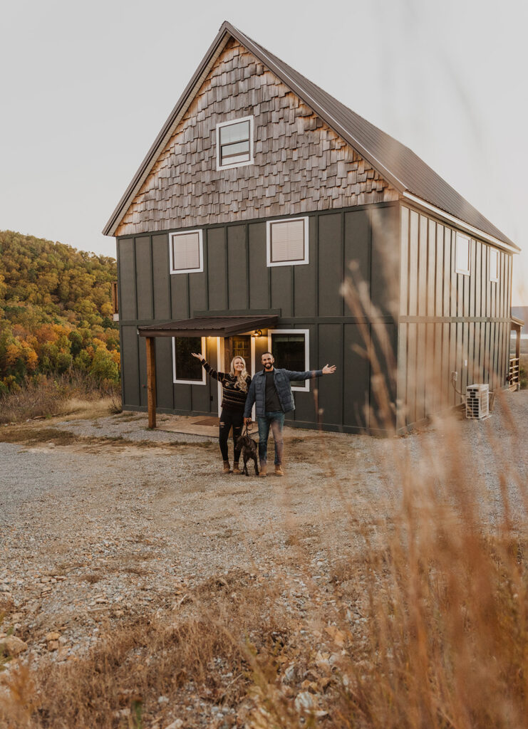 A couple stands together with their dog in front of their cabin in broken bow before getting ready for their elopement in Oklahoma. 