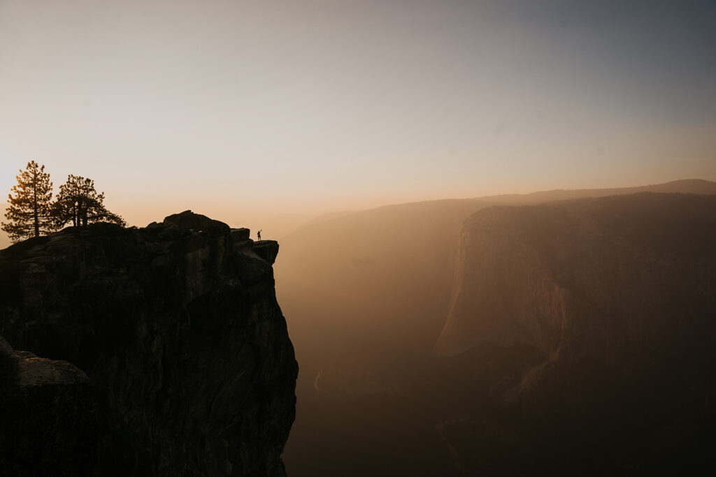 A bride stands on taft point on her wedding day in yosemite national park. 