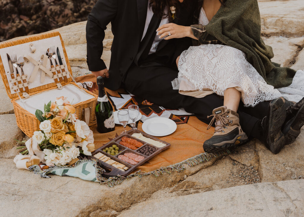 A couple sits for a picnic in acadia national park on their wedding day