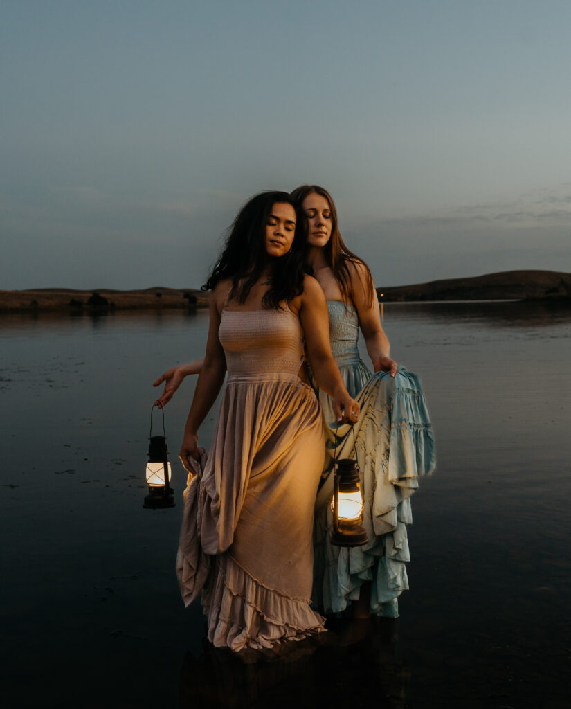 a lgbtq couple getting married in oklahoma at night stand in a lake with lanterns.